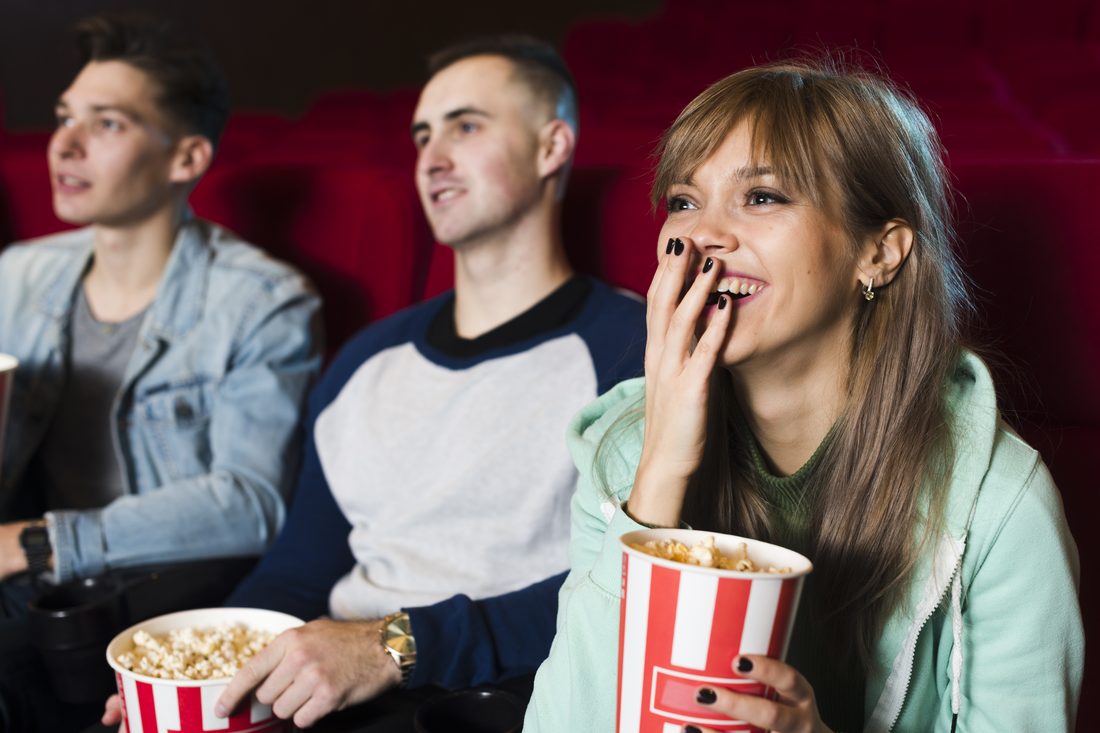 Troje znajomych z popcornem na seansie w kinie