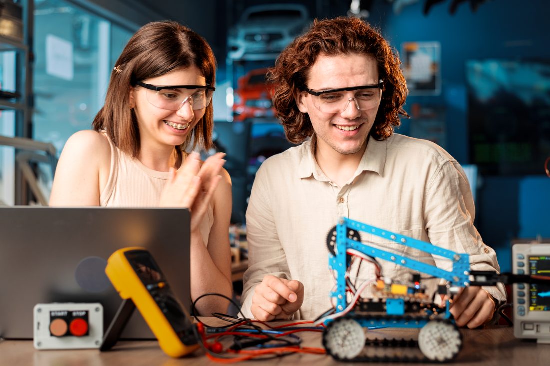 Studentka i student w okularach ochronnych budują robota w pracowni